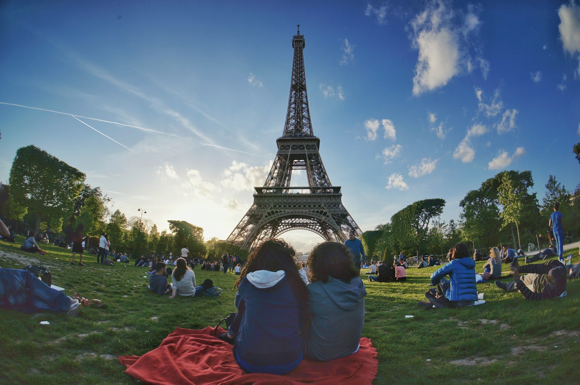 Fiatalok pihennek a Champ de Mars füvén, a háttérben az Eiffel-torony